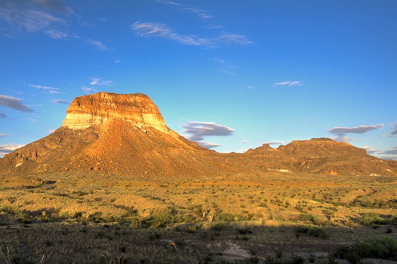 Cerro Castellan - also known as Castolon Peak or Castellan Peak, is a conical volcanic mountain in West Texas that rises 1000 feet above the desert floor (3,293 feet above sea level) in Big Bend National Park. Cerro Castellan itself is part of an ancient series of summits once known as the Corazones Peaks that has since succumbed to millennia of erosion by wind, precipitation, searing heat and bitterly cold winters. Geologically, this ancient mountain range remnant is a high stack of volcanic rocks, including ash, lava, and tuffaceous rocks. It is capped by a dense lava flow underlain by various tuffs and basalts. A somewhat northwest fault cuts the eastern face of Cerro Castellan. Although little vegetation grows on the sheer cliffs and steep, pointed profile of its peak, the lower slopes of Cerro Castellan support a sparse growth of Chihuahuan Desert scrub, including most prominently such characteristic species as creosote bush and ocotillo.