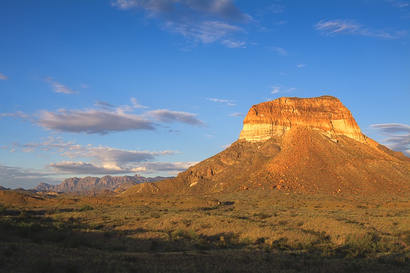 Cerro Castellan - also known as Castolon Peak or Castellan Peak, is a conical volcanic mountain in West Texas that rises 1000 feet above the desert floor (3,293 feet above sea level) in Big Bend National Park. Cerro Castellan itself is part of an ancient series of summits once known as the Corazones Peaks that has since succumbed to millennia of erosion by wind, precipitation, searing heat and bitterly cold winters. Geologically, this ancient mountain range remnant is a high stack of volcanic rocks, including ash, lava, and tuffaceous rocks. It is capped by a dense lava flow underlain by various tuffs and basalts. A somewhat northwest fault cuts the eastern face of Cerro Castellan. Although little vegetation grows on the sheer cliffs and steep, pointed profile of its peak, the lower slopes of Cerro Castellan support a sparse growth of Chihuahuan Desert scrub, including most prominently such characteristic species as creosote bush and ocotillo.
